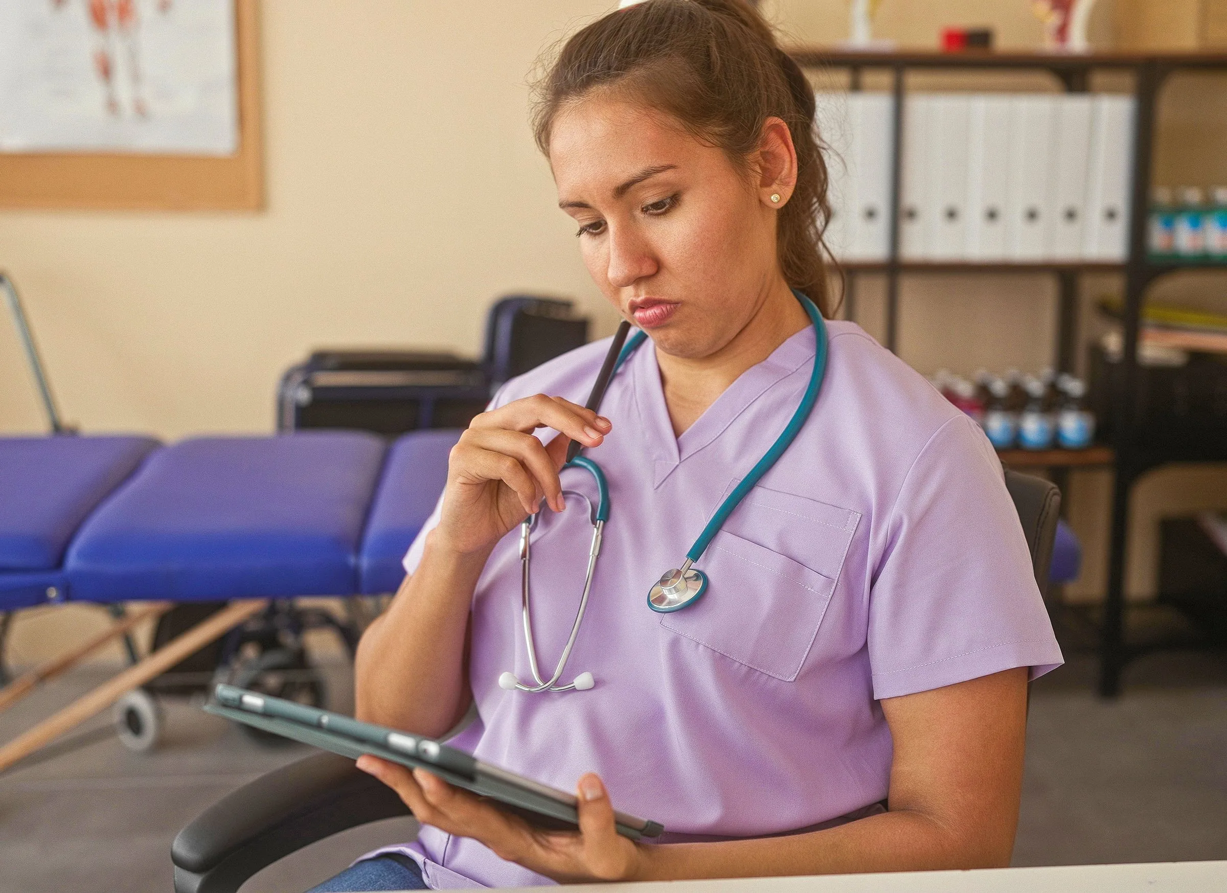 A therapist concentrating on a practice note on a tablet in a therapy gym